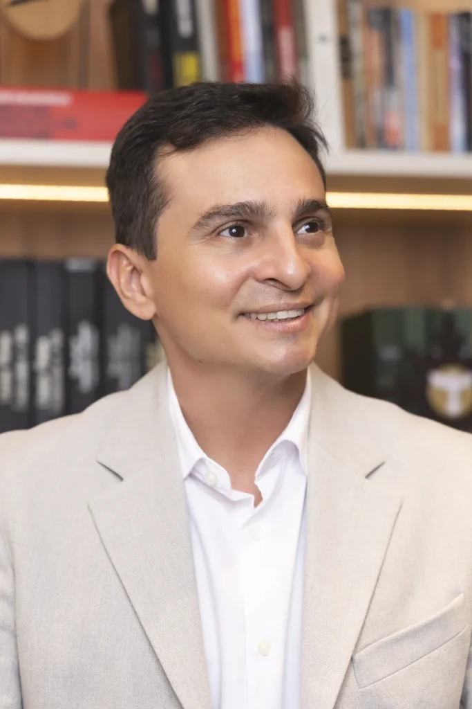 Dr. Eduardo Furlani diante da estante do consultório, em Fortaleza